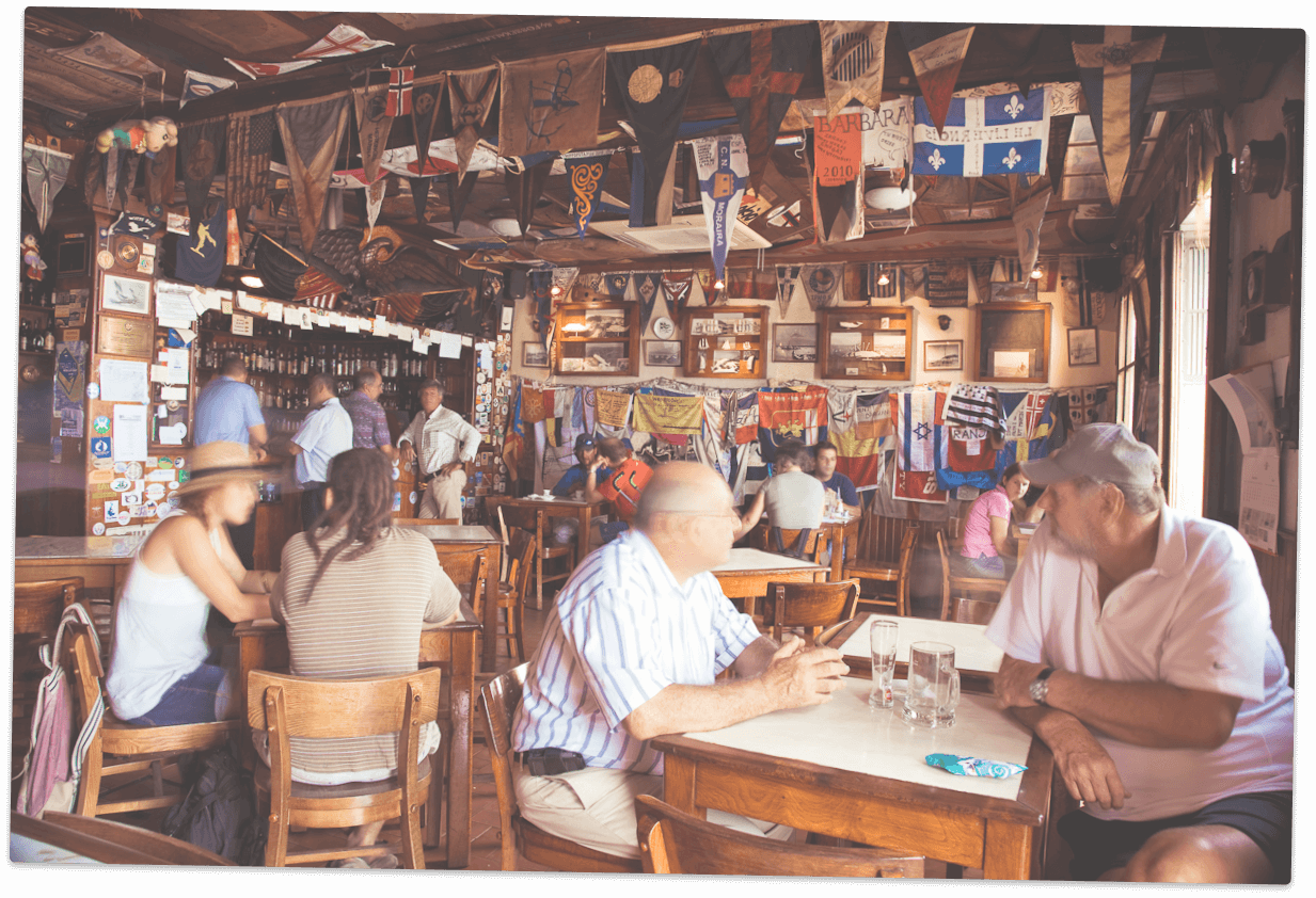  Fotografia antiga do interior do Peter Cafe Sport com o proprietário e alguns membros do navio H.M.S. Lusitania II da Royal Navy. 