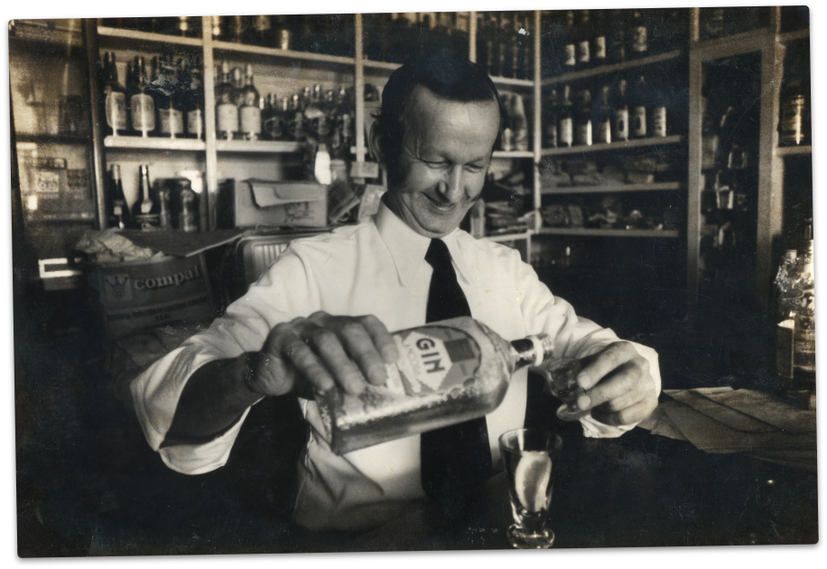   Fotografia antiga de um barman a servir o gin do mar no interior do peter café sport 