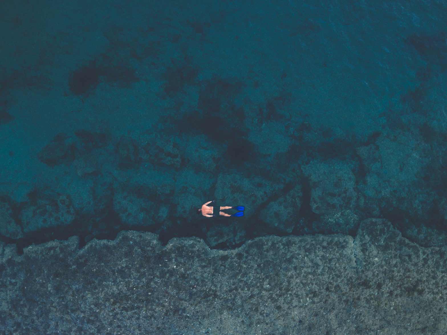 Um homem a mergulhar no mar azul do Faial, nos Açores